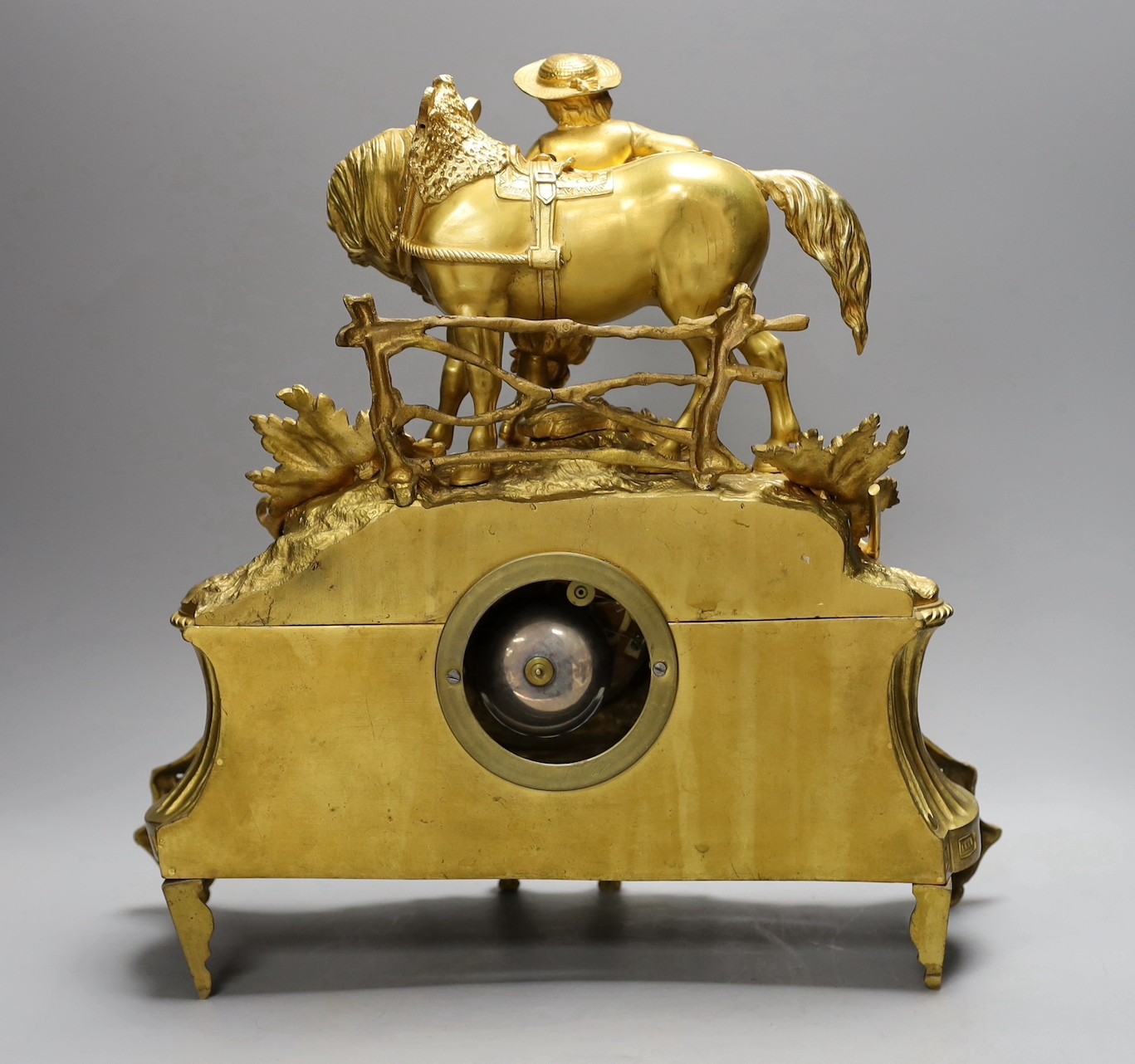 A 19th century French gilt brass mantel clock with man and horse, with key and pendulum, 38cm tall